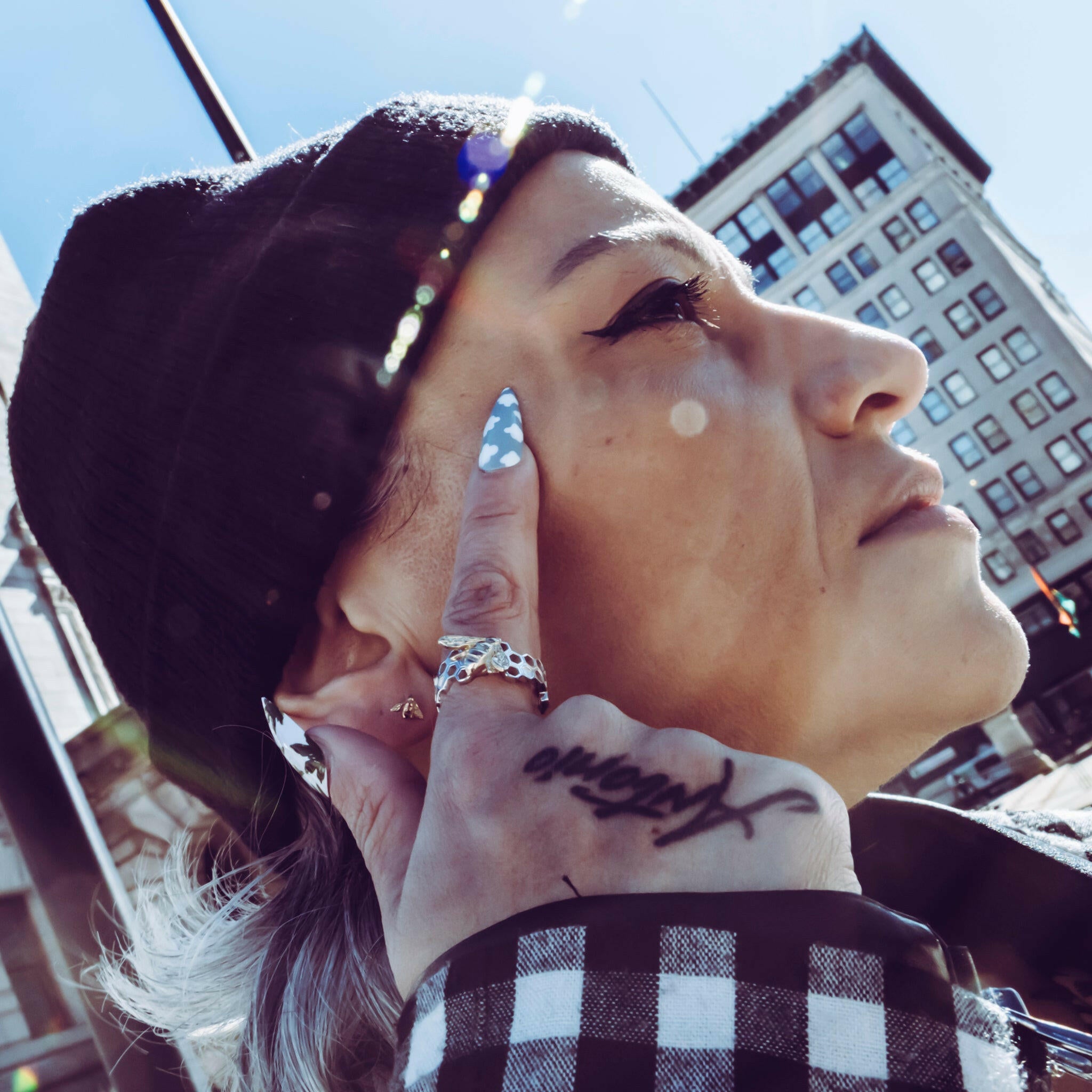 lady lokking off into the distance pointing at her temple showcasing the bee rings and baby bee studs 14K Gold