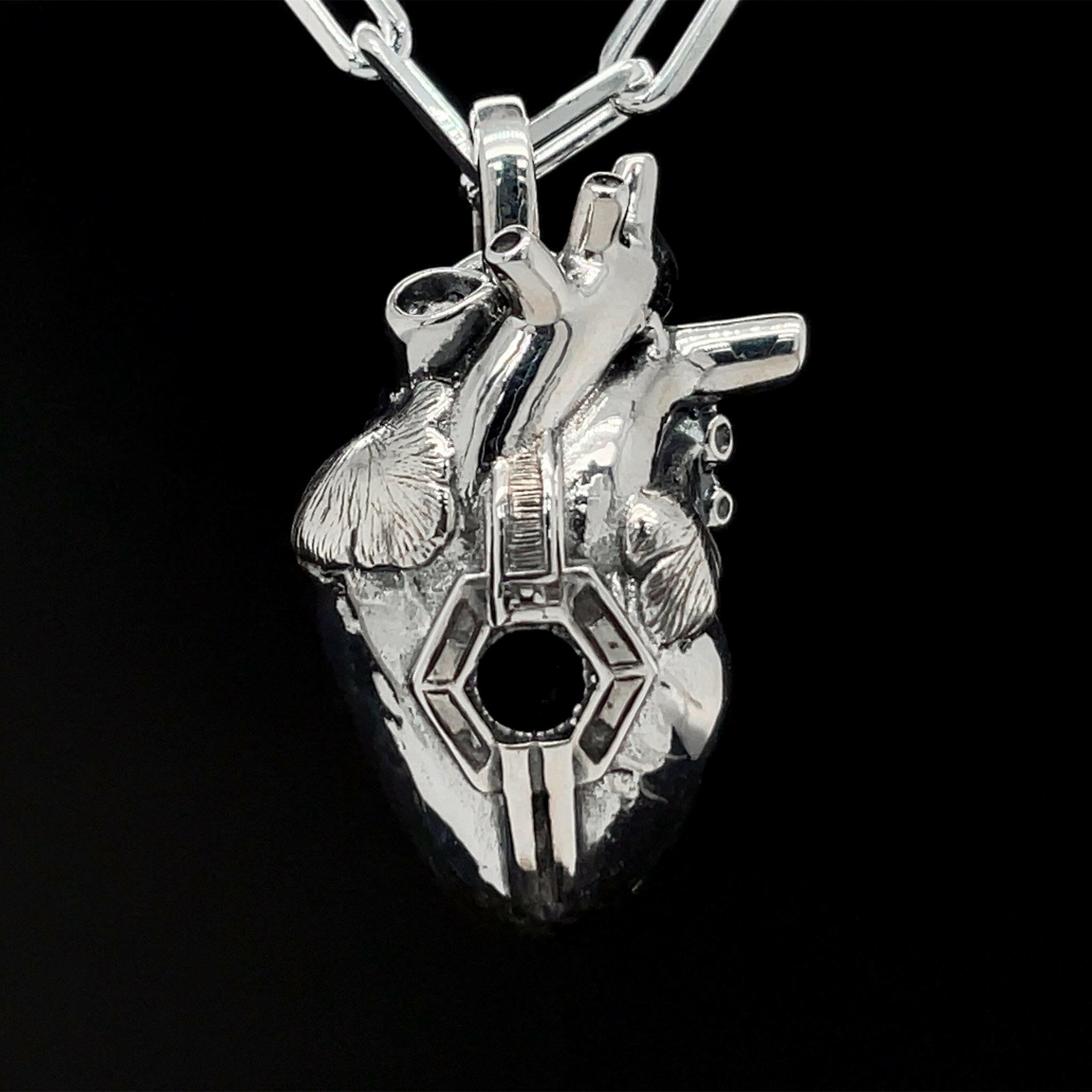 Front view of fatal flaw pendant made of sterling silver , pendant resembles an atomical heart with a hexagonal hole in the center.