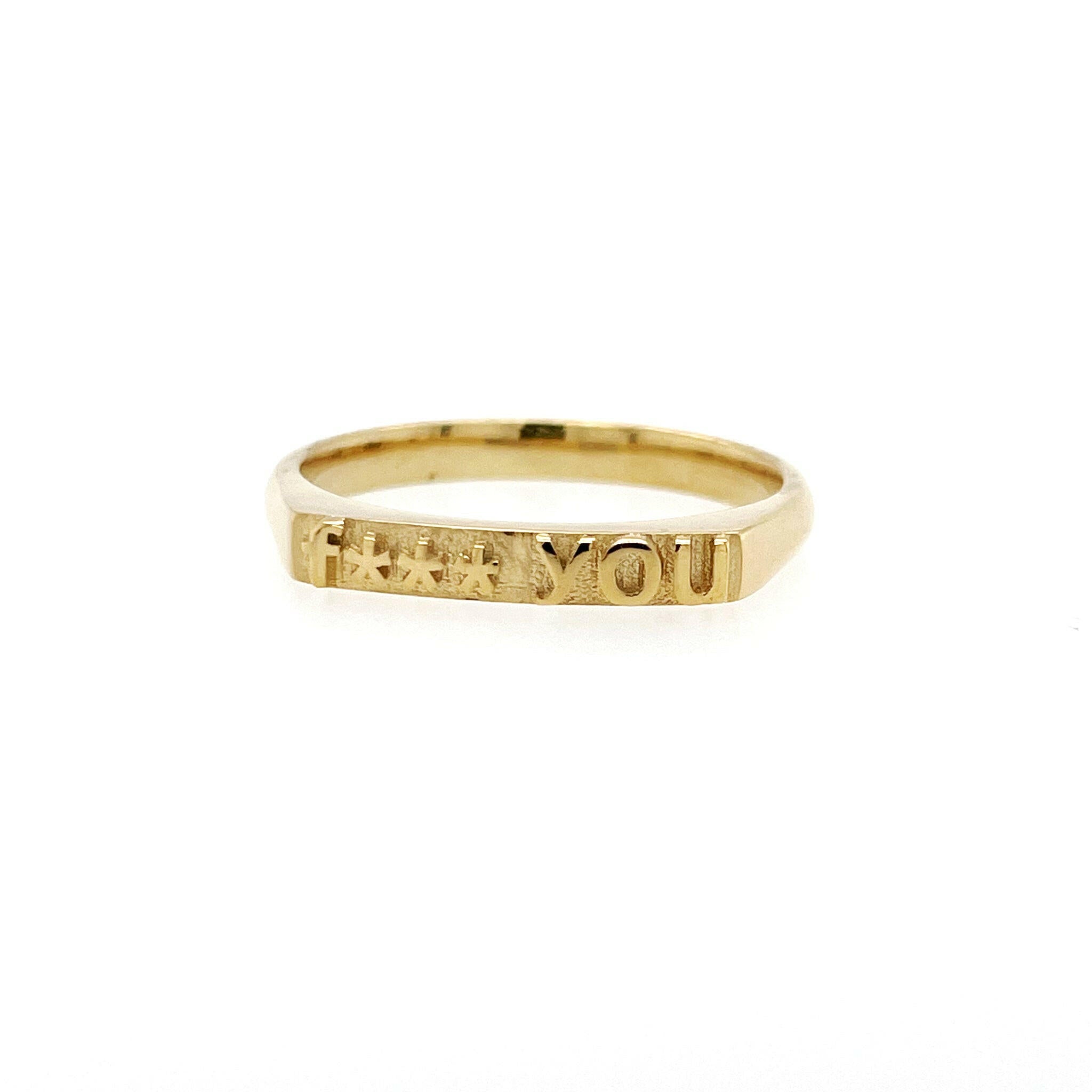 front view of ring in 14 karat yellow gold with text that reads "fuck you" but with 4 asterisks to censor fuck, therefore says "f*** you"