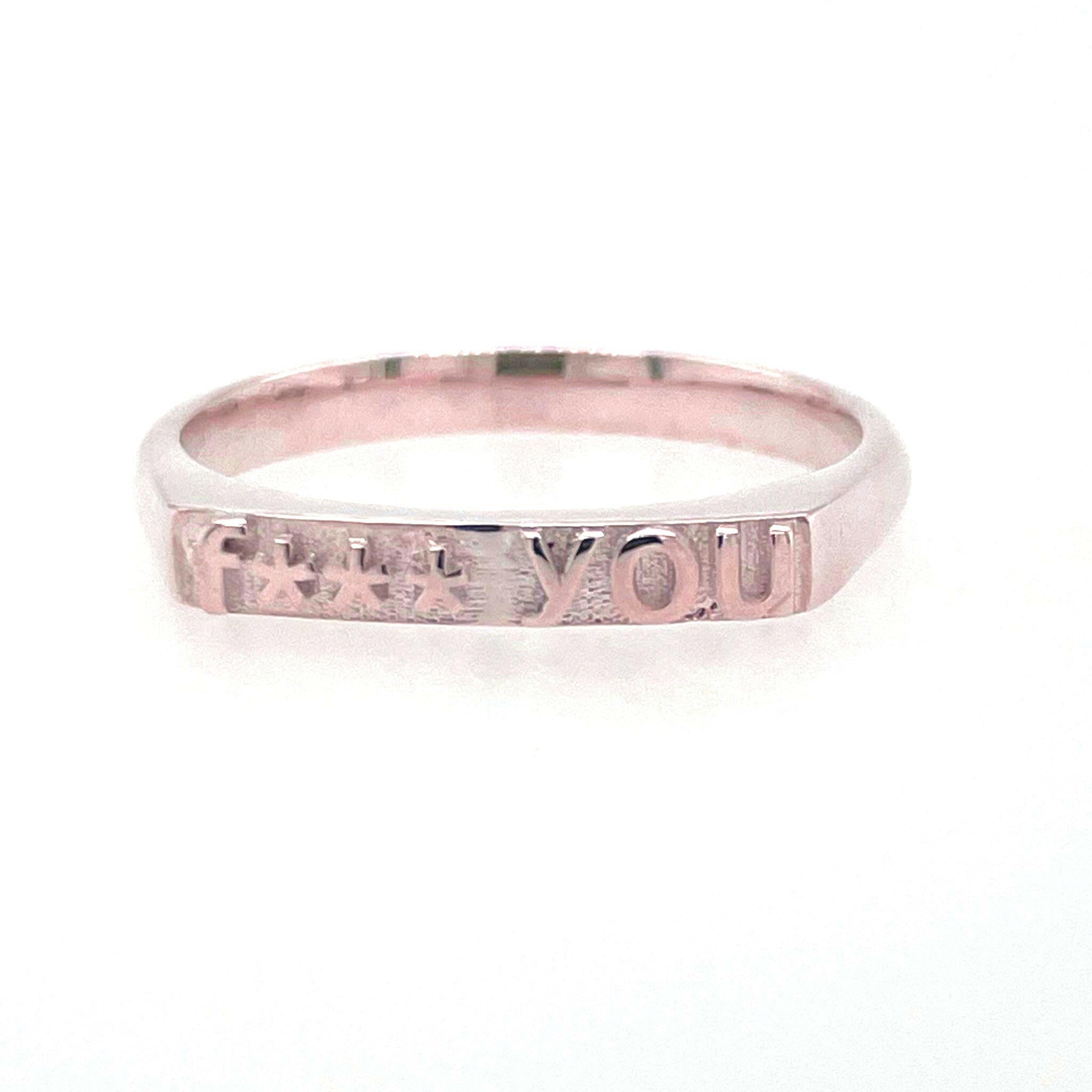 front view of ring in 14 karat rose gold with text that reads "fuck you" but with 4 asterisks to censor fuck, therefore says "f*** you"