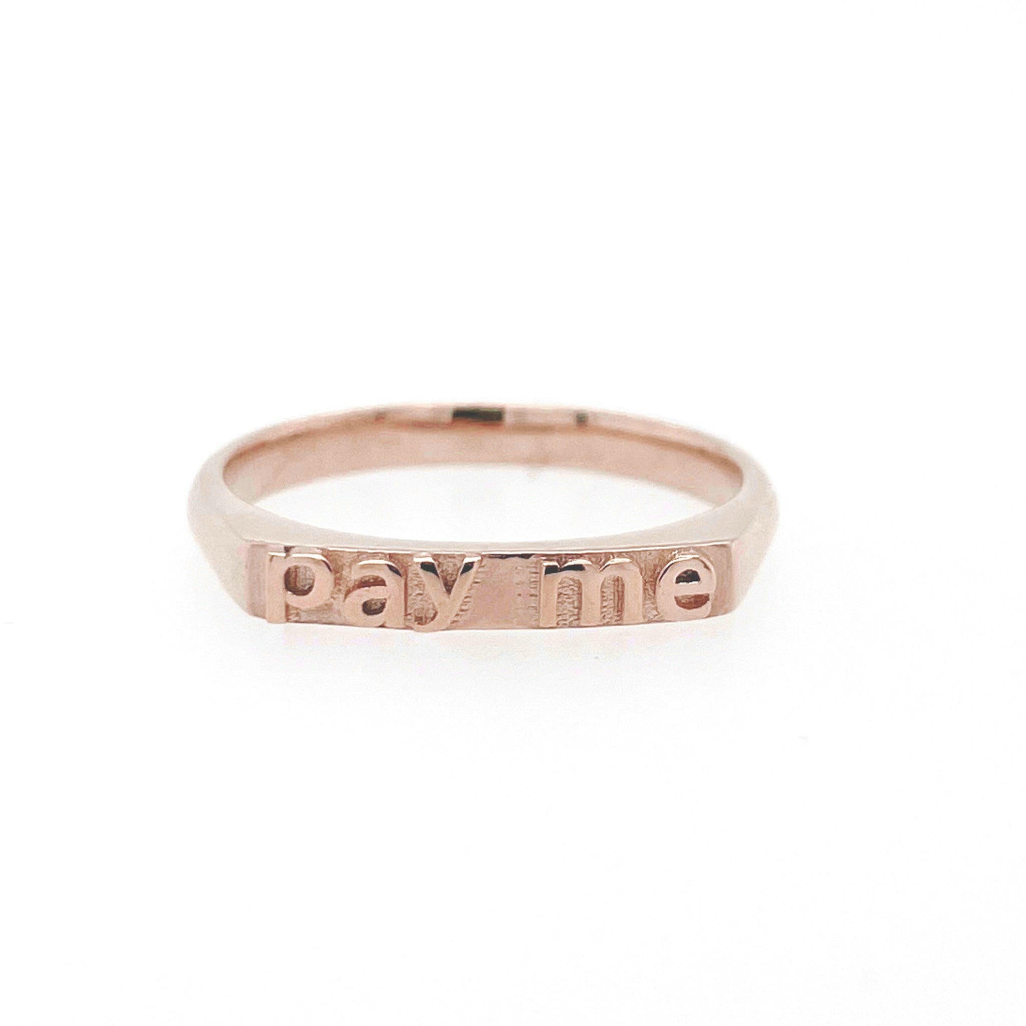 front view of 14 karat rose gold ring with text that reads "pay me"