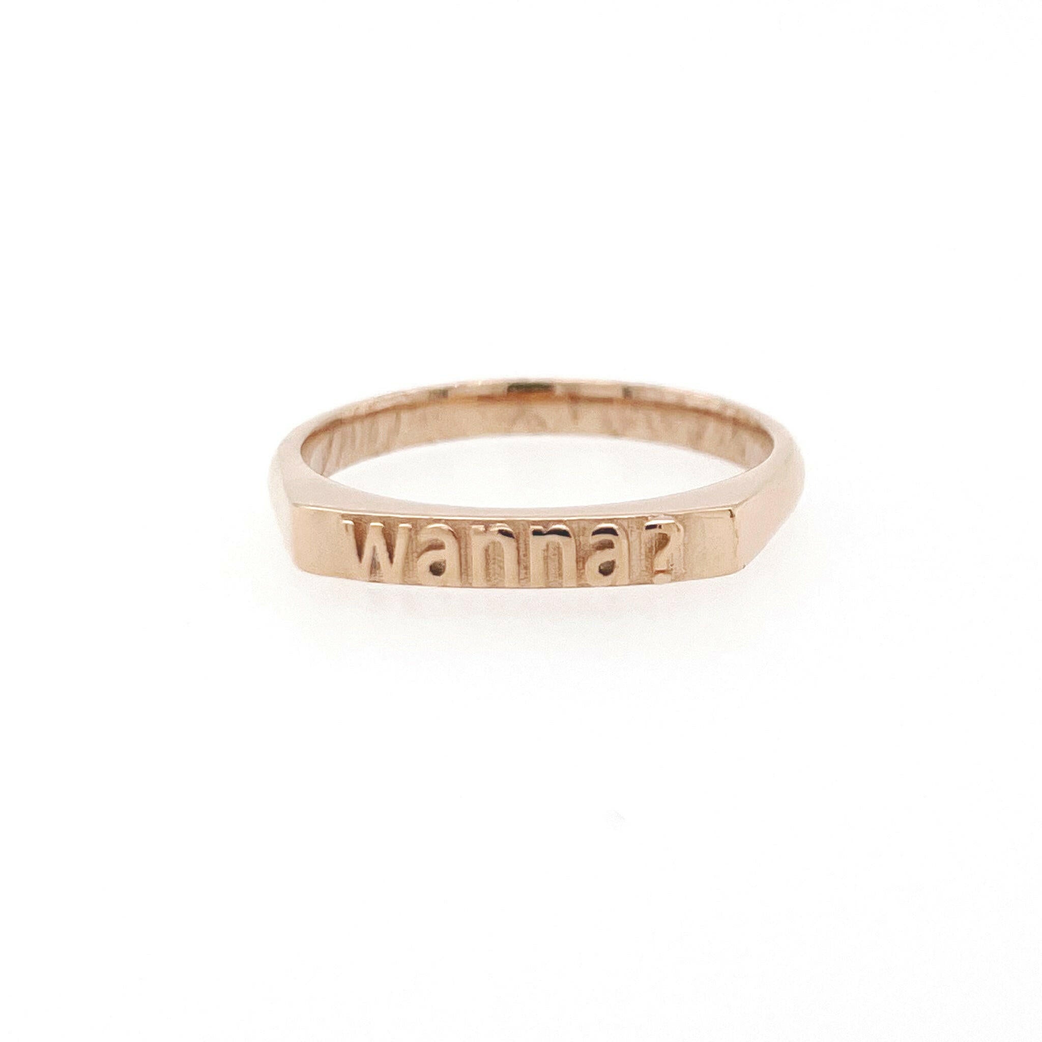 front view of  14 karat rose gold ring with text that reads "wanna?"